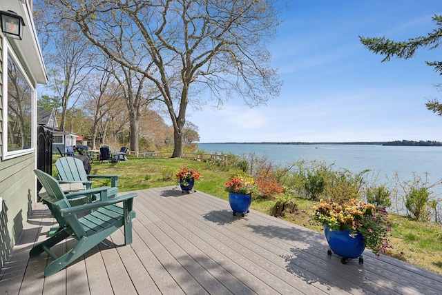 wooden terrace featuring a water view and a yard