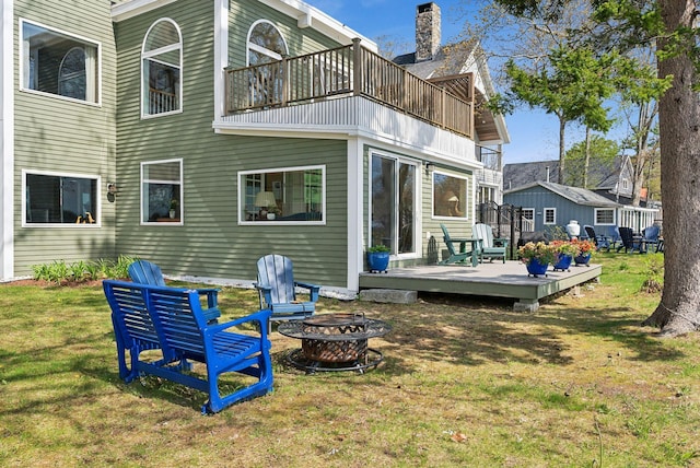 back of house featuring an outdoor fire pit, a balcony, a lawn, and a deck