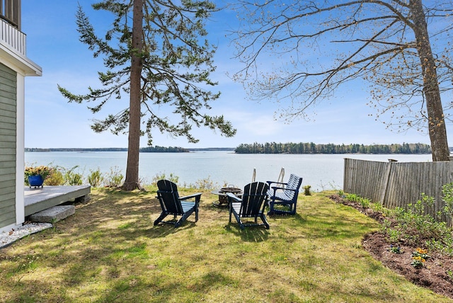 view of yard featuring a water view, fence, and a fire pit
