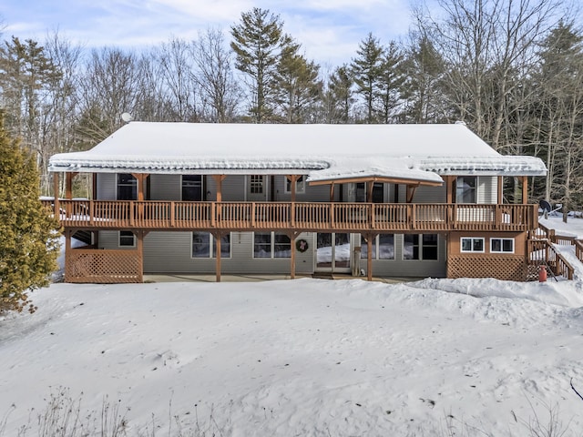 snow covered back of property featuring a deck