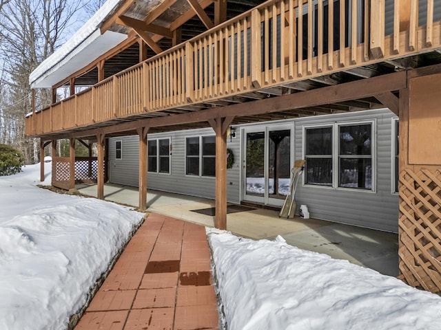 snow covered rear of property with a deck