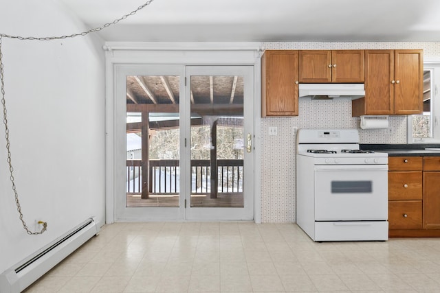 kitchen featuring under cabinet range hood, white range with gas stovetop, baseboard heating, brown cabinetry, and dark countertops