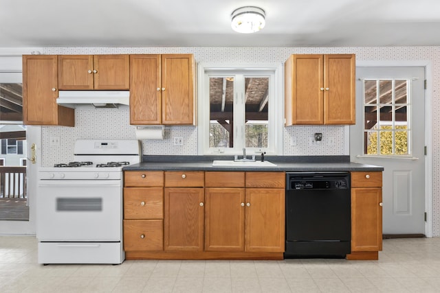 kitchen with white gas range oven, dishwasher, dark countertops, under cabinet range hood, and a sink