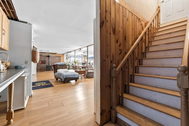 staircase featuring ceiling fan, wood walls, and wood finished floors