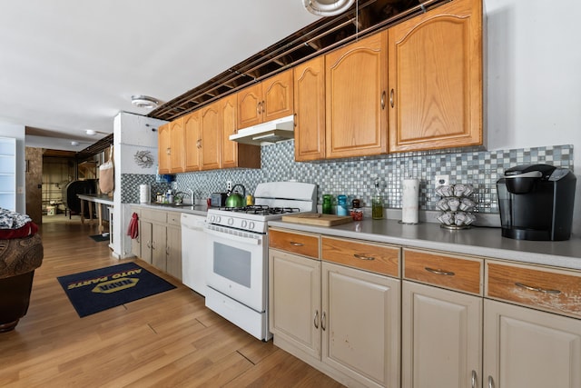 kitchen featuring light wood-type flooring, white appliances, light countertops, and under cabinet range hood