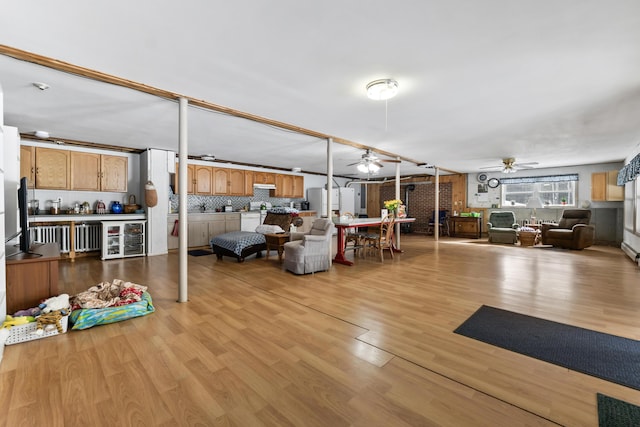 interior space with visible vents, ceiling fan, wine cooler, a wood stove, and light wood-style floors