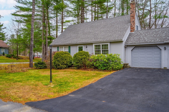 cape cod house featuring a garage, a front lawn, roof with shingles, a chimney, and driveway