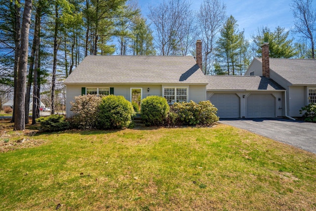 view of front of property featuring aphalt driveway, a front lawn, roof with shingles, and a garage