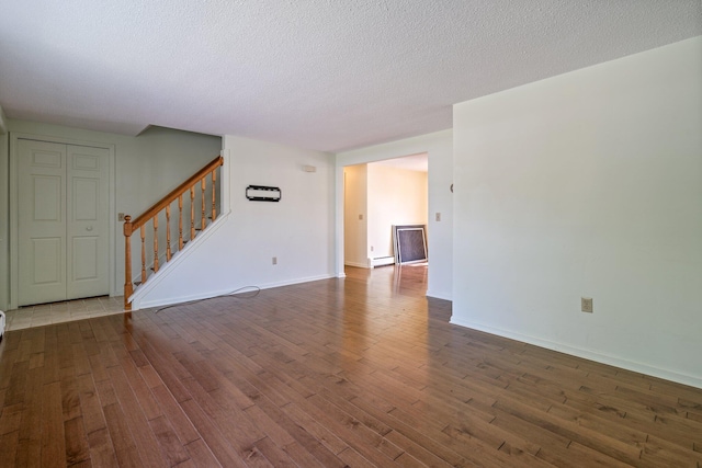 unfurnished living room with stairway, a textured ceiling, and wood finished floors