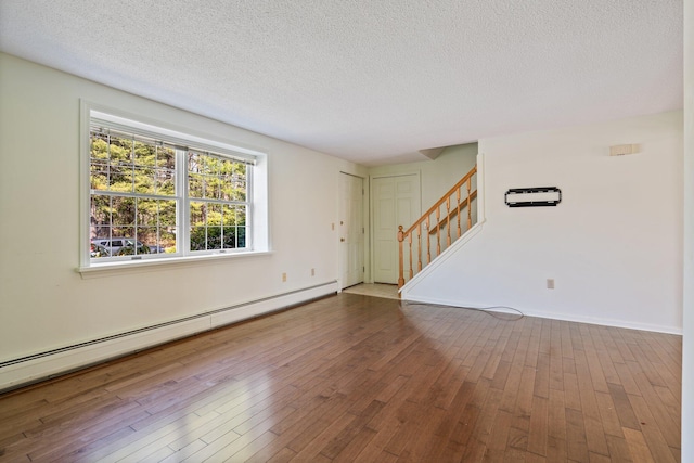 unfurnished living room with wood-type flooring, stairs, baseboards, baseboard heating, and a textured ceiling