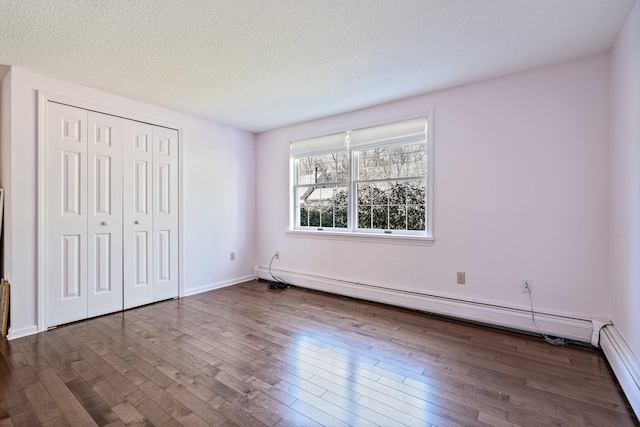 unfurnished bedroom featuring a closet, a textured ceiling, dark wood-style floors, and a baseboard radiator
