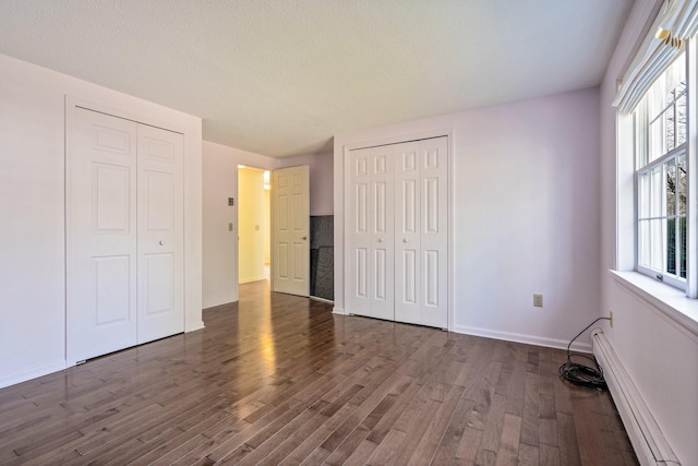 unfurnished bedroom with baseboards, baseboard heating, and dark wood finished floors