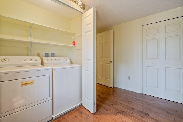 laundry area featuring laundry area, a textured ceiling, baseboards, light wood finished floors, and washer and clothes dryer