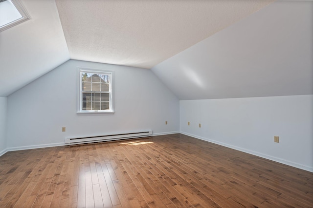 additional living space featuring baseboards, vaulted ceiling, hardwood / wood-style flooring, and a baseboard radiator