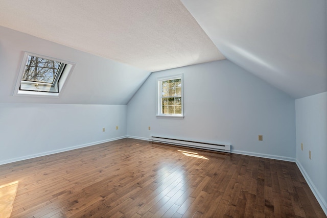 additional living space featuring baseboards, a baseboard radiator, hardwood / wood-style flooring, and lofted ceiling with skylight