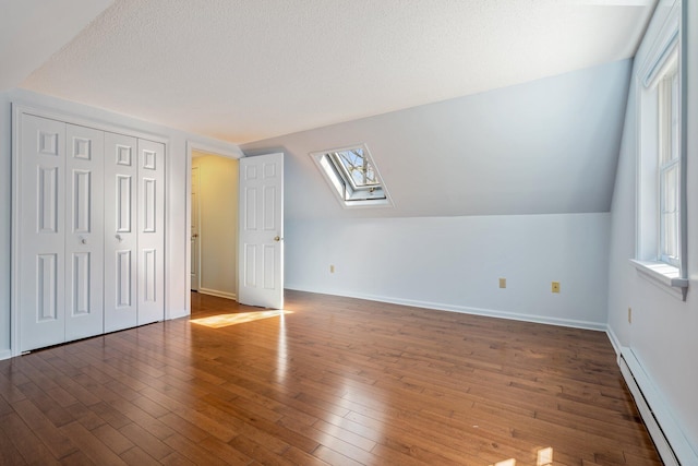 additional living space with a skylight, baseboards, a baseboard radiator, and a wealth of natural light