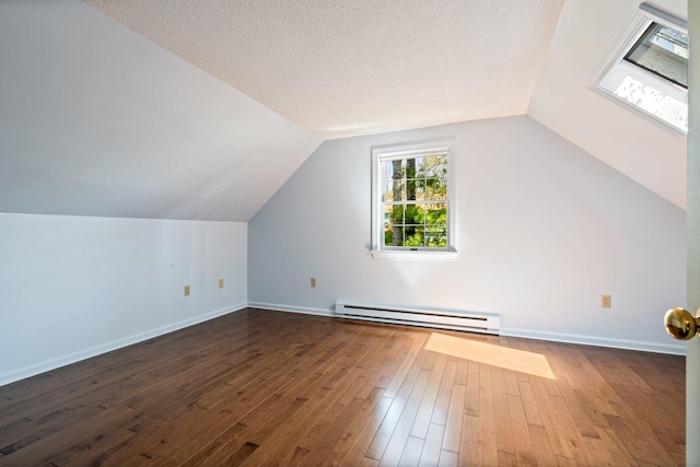 additional living space with baseboards, a baseboard heating unit, dark wood finished floors, and vaulted ceiling