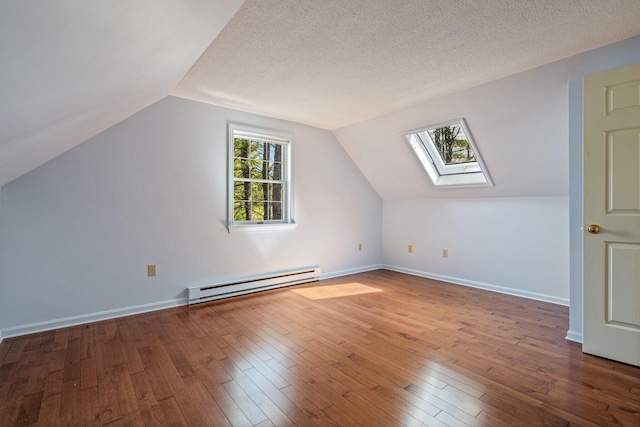 bonus room with a baseboard radiator, vaulted ceiling with skylight, and hardwood / wood-style flooring