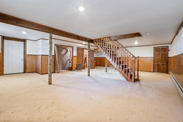 finished basement with a wainscoted wall, carpet, wood walls, and stairs