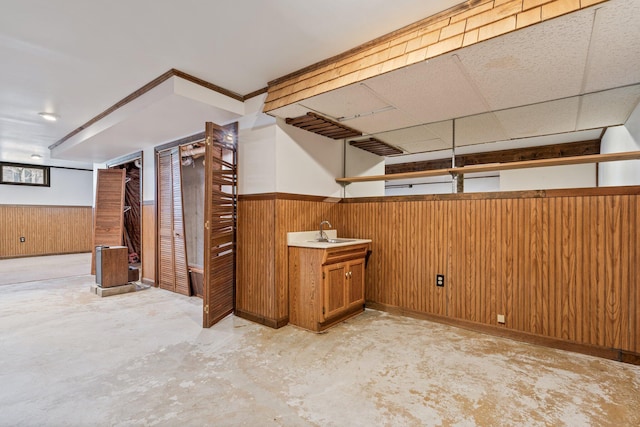finished below grade area with wood walls, wainscoting, and a sink