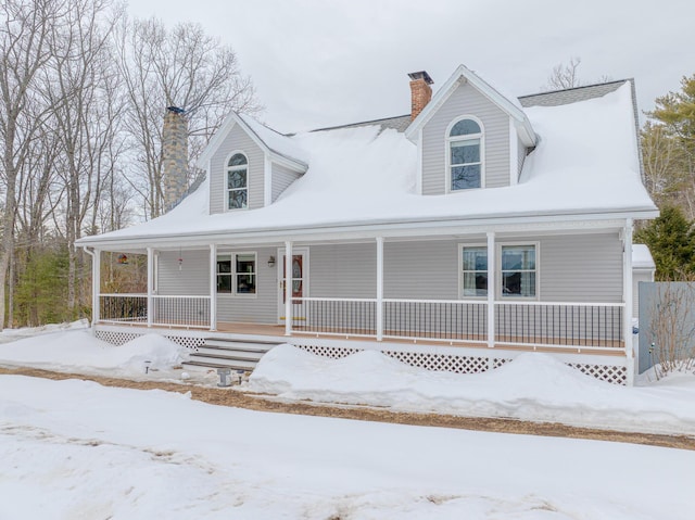 cape cod-style house with covered porch and a chimney