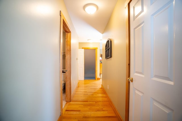 corridor featuring baseboards and light wood finished floors