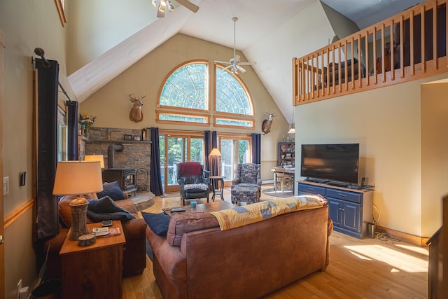 living room with high vaulted ceiling, a wood stove, light wood-type flooring, and a ceiling fan