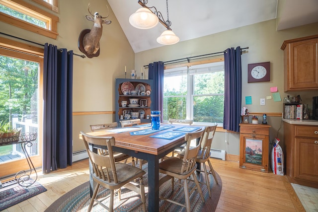 dining area with lofted ceiling, light wood finished floors, baseboard heating, and a wealth of natural light