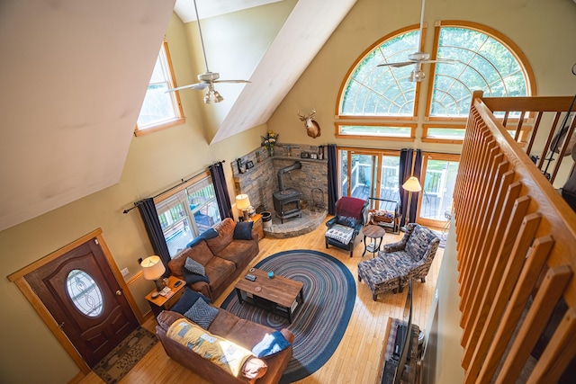 living area with ceiling fan, hardwood / wood-style floors, and a wood stove