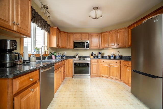 kitchen with appliances with stainless steel finishes, brown cabinets, a sink, and light floors