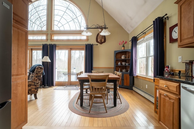 dining space featuring light wood-type flooring, a baseboard radiator, and high vaulted ceiling