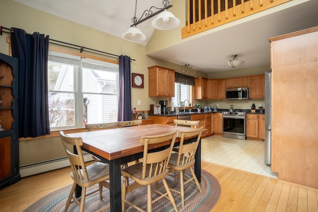 dining room with baseboard heating, light wood-type flooring, and a towering ceiling