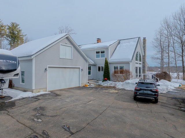 view of front of home featuring aphalt driveway, a chimney, and an attached garage