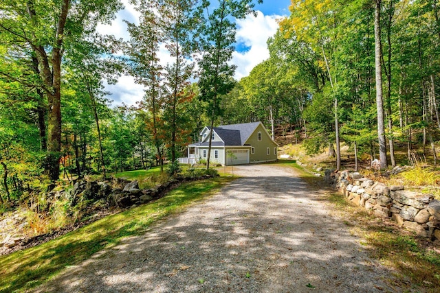 view of front facade with a garage, gravel driveway, and a wooded view