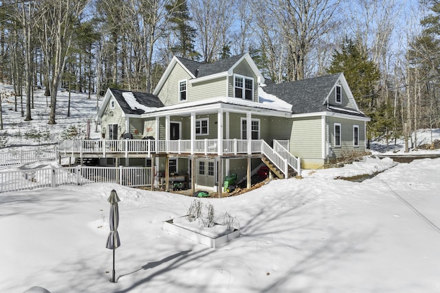 snow covered rear of property featuring stairway