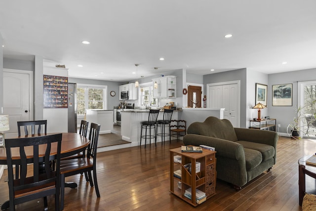 living area with baseboards, dark wood-style flooring, and recessed lighting