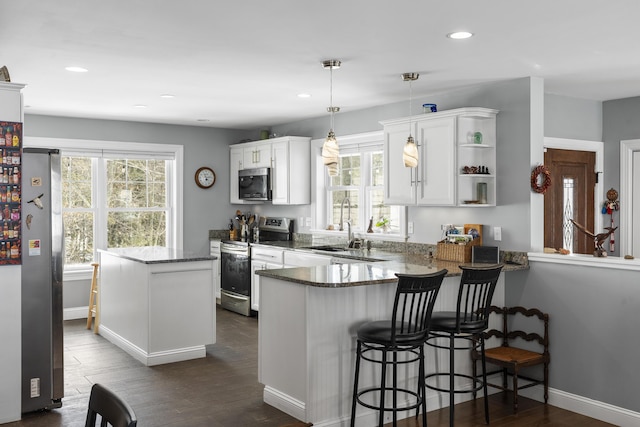 kitchen featuring white cabinets, a kitchen island, appliances with stainless steel finishes, dark wood-type flooring, and open shelves