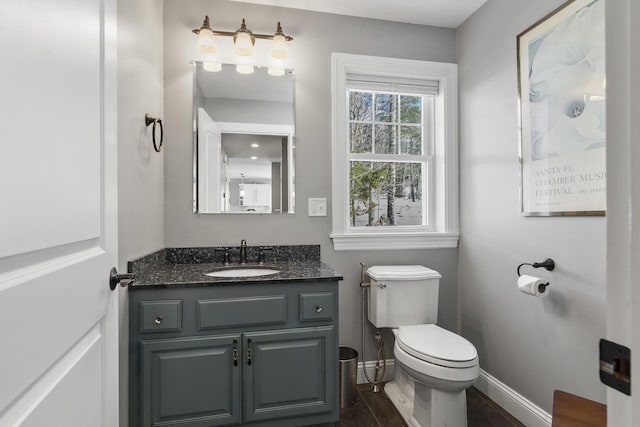 bathroom with toilet, baseboards, and vanity