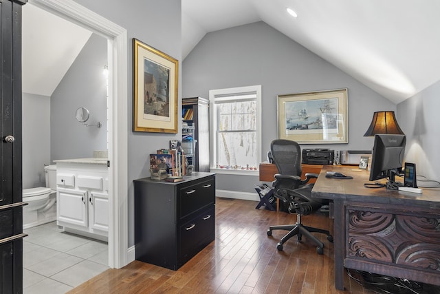 office area featuring baseboards, vaulted ceiling, and light wood finished floors