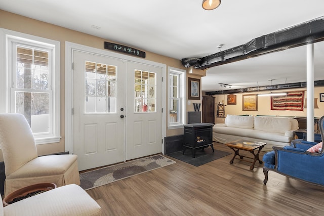 entrance foyer with french doors, wood finished floors, and a wood stove