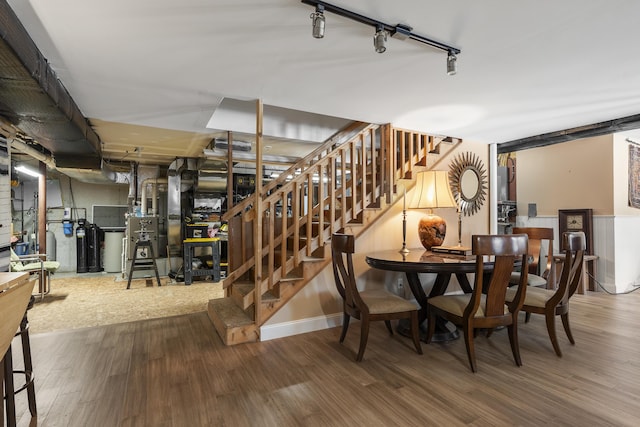 dining space with stairway, wood finished floors, and rail lighting