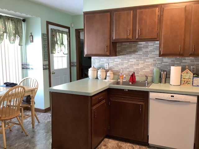 kitchen with tasteful backsplash, dishwasher, a peninsula, light countertops, and a sink