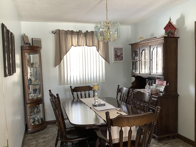 dining room with a notable chandelier, a textured ceiling, and baseboards