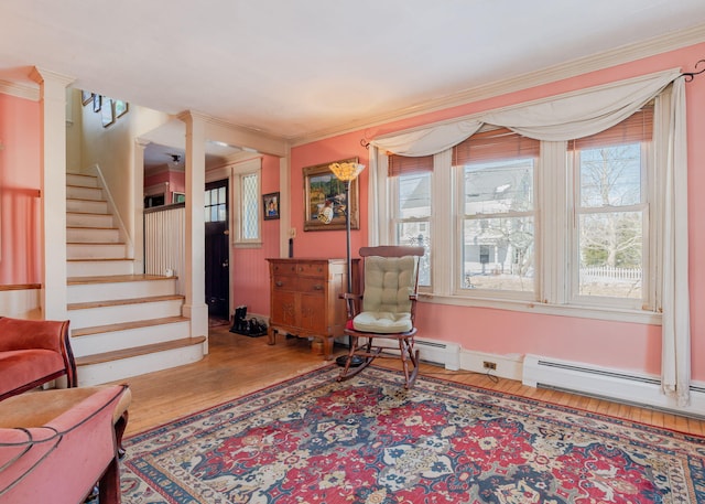 sitting room with wood finished floors, baseboards, ornamental molding, stairway, and decorative columns