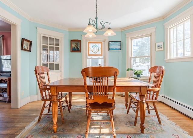 dining area with ornamental molding, baseboards, light wood finished floors, and an inviting chandelier