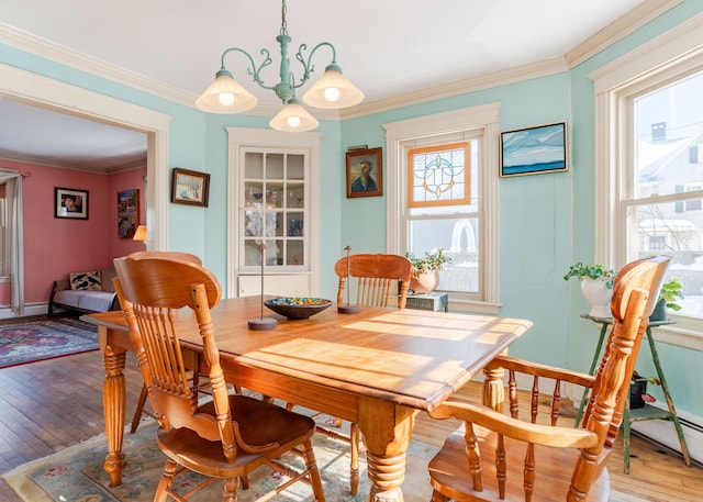 dining space featuring a notable chandelier, ornamental molding, baseboards, and light wood-style floors