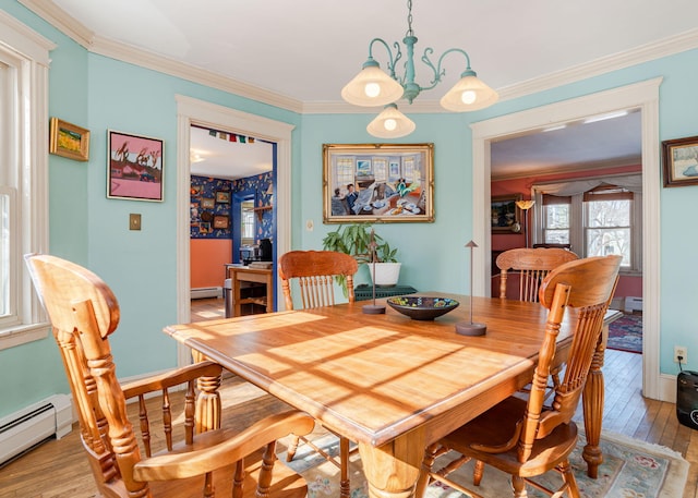 dining area featuring a baseboard heating unit, ornamental molding, light wood finished floors, and baseboards