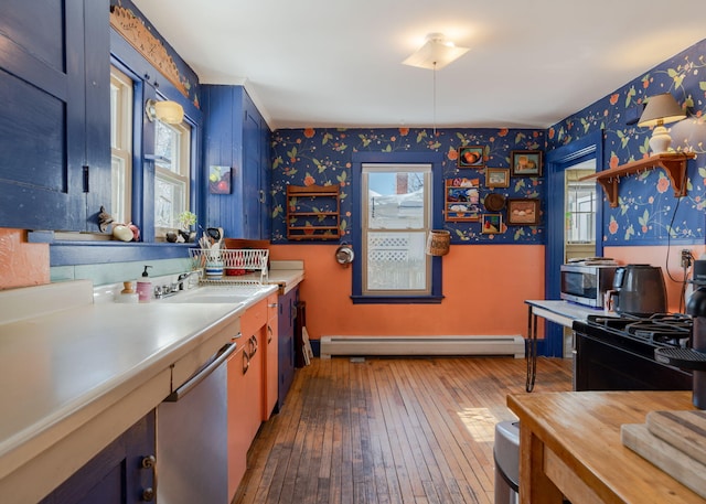 kitchen featuring a sink, light countertops, baseboard heating, dark wood finished floors, and wallpapered walls