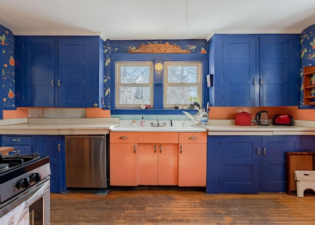 kitchen featuring blue cabinets, gas stove, light countertops, and refrigerator