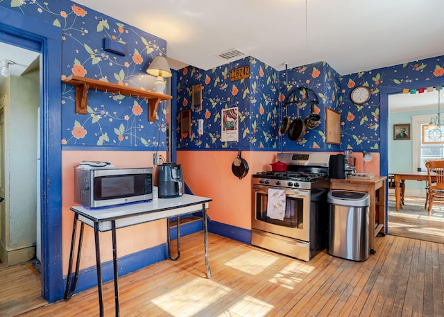 kitchen featuring visible vents, hardwood / wood-style floors, appliances with stainless steel finishes, baseboards, and wallpapered walls